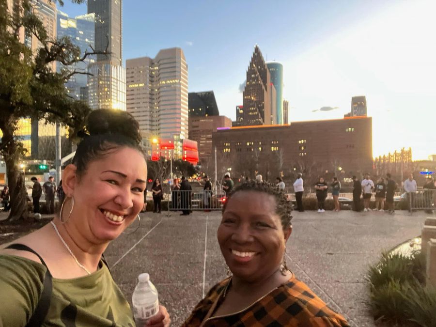 Two volunteers smiling at a clothing drive with the Houston skyline behind them